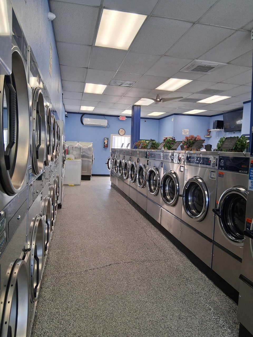 Full aisle view of washers and stacked dryers at a clean, well-maintained laundromat in Hemet, CA