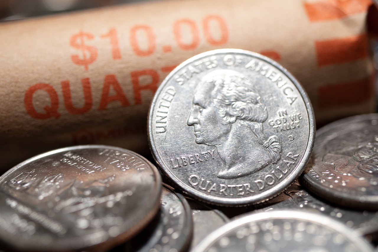 Close-up of stacked quarters with a blurred red dollar amount glowing in the background — the coins that power coin operated laundry at The Laundry Basket in Hemet, CA.